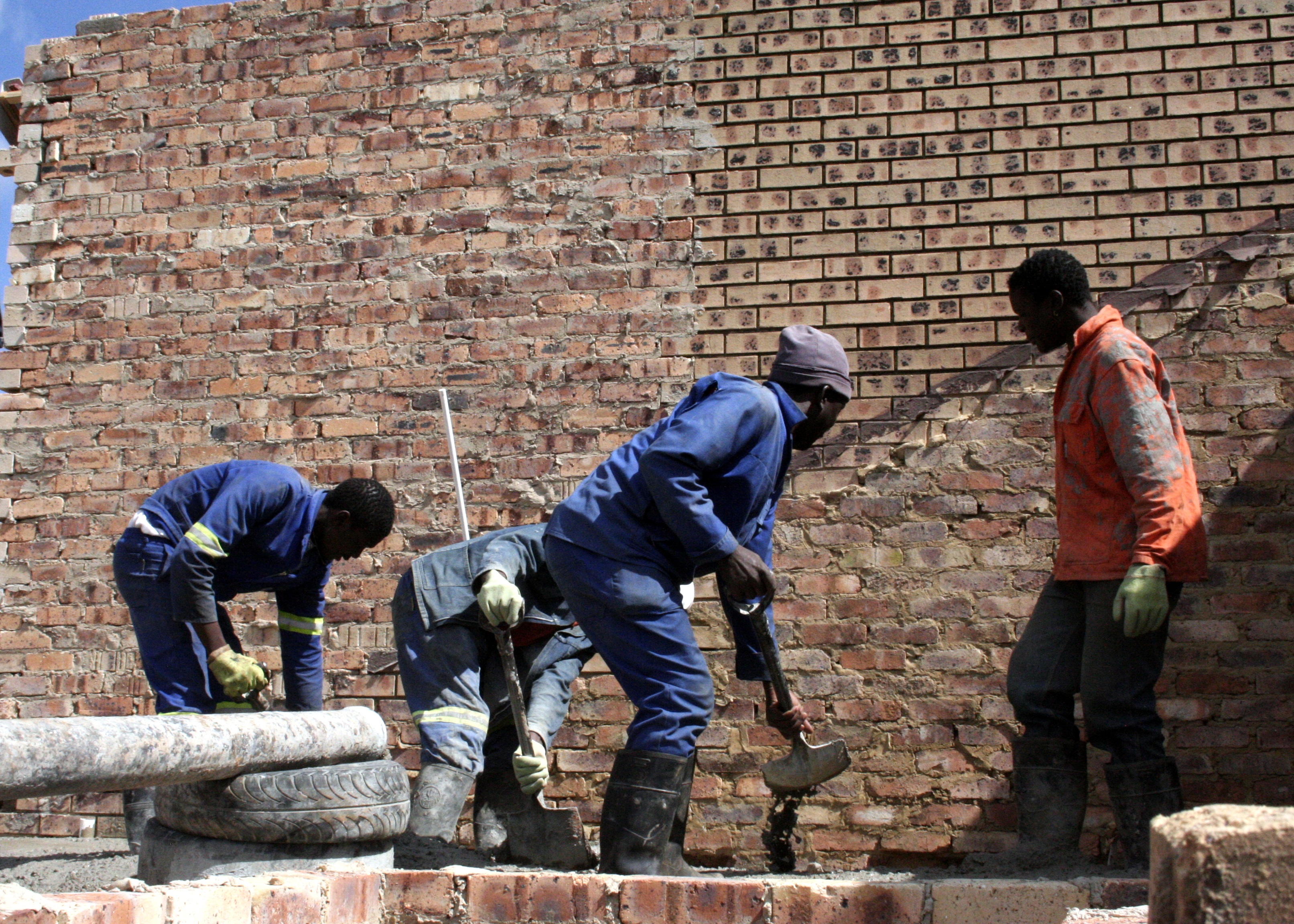 Construction team in hard hats and high-vis vests reviewing plans on site